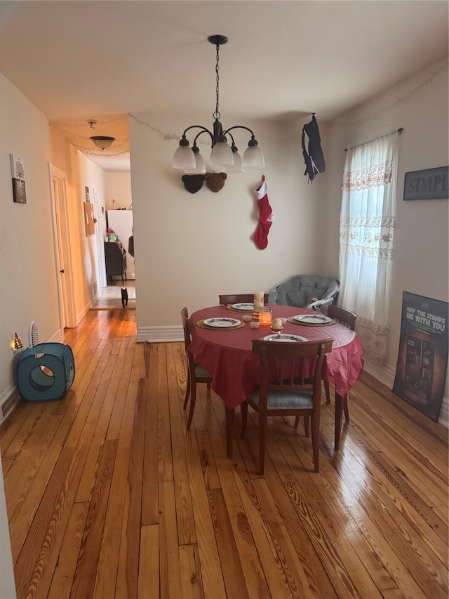 dining room with a chandelier, baseboards, and hardwood / wood-style floors