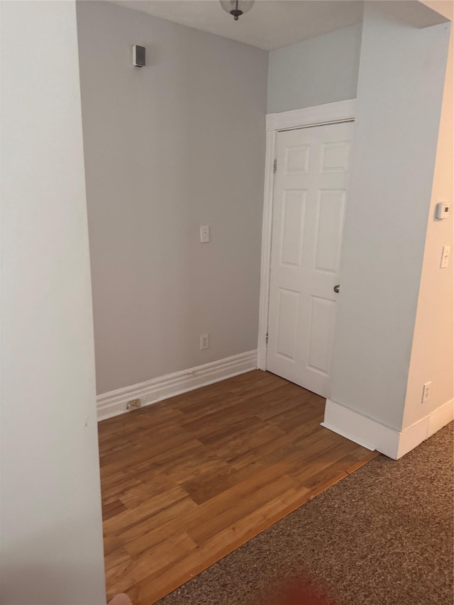 spare room with baseboards and wood finished floors