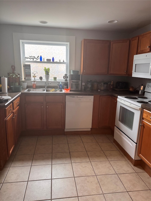 kitchen featuring white appliances, light tile patterned floors, dark countertops, and a sink