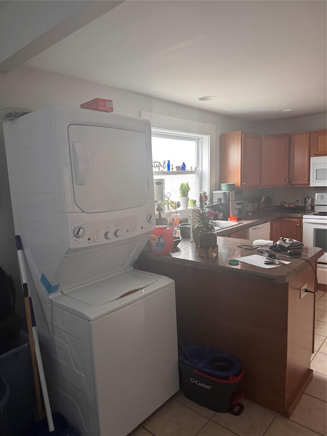 washroom with laundry area, stacked washer / dryer, light tile patterned floors, and a sink