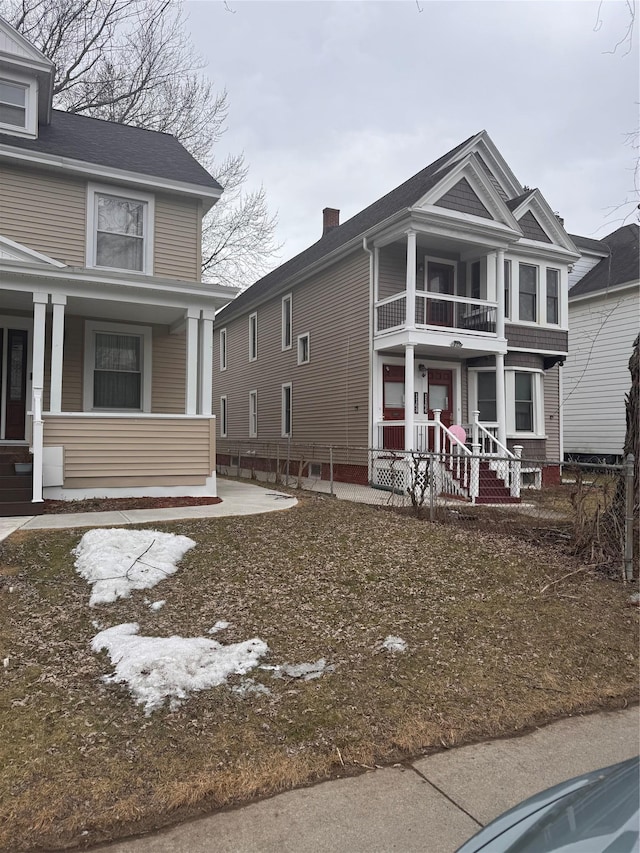 view of front of house with a balcony, a porch, and a chimney