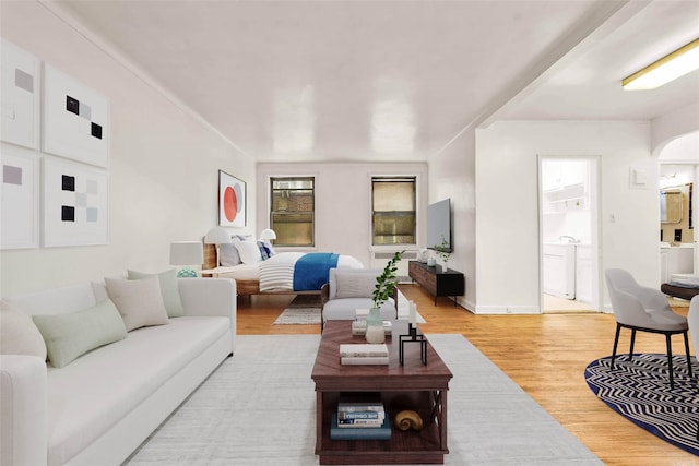 living room with light wood-style floors, arched walkways, and baseboards