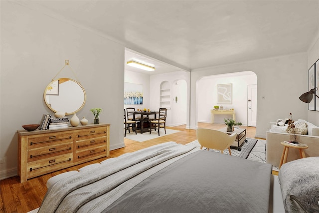 bedroom featuring baseboards, arched walkways, and wood finished floors