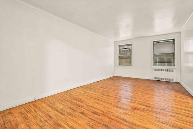 unfurnished room featuring radiator, baseboards, and wood-type flooring