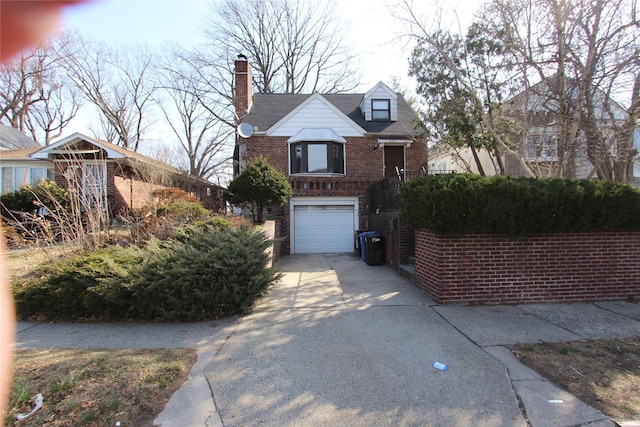 view of front of home featuring a garage, brick siding, concrete driveway, and a chimney