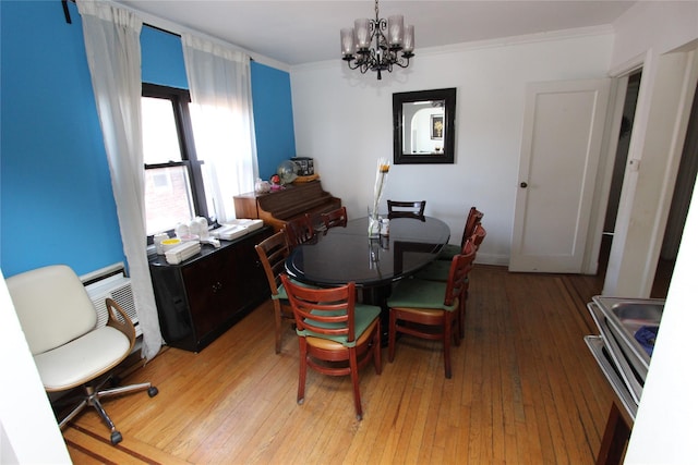 dining area featuring an inviting chandelier, crown molding, and light wood-style flooring