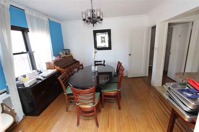 dining area with a chandelier, light wood-style floors, and ornamental molding