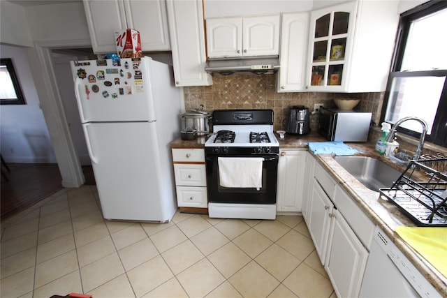 kitchen featuring white appliances, light tile patterned floors, a sink, white cabinets, and under cabinet range hood