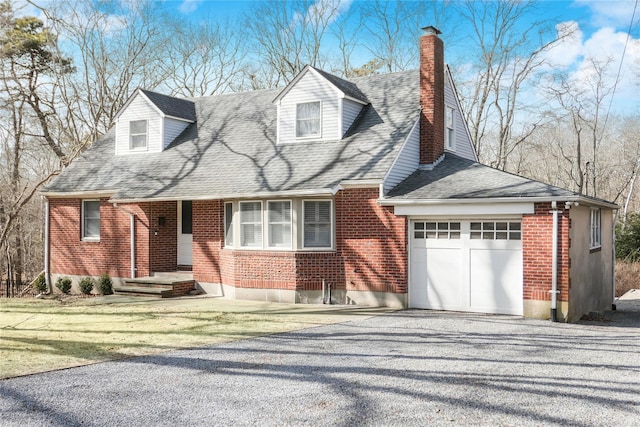 cape cod home with brick siding, a garage, driveway, and a chimney