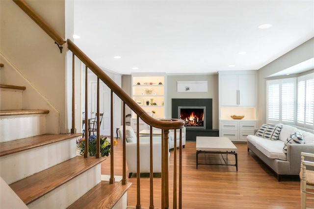 interior space with recessed lighting, a warm lit fireplace, and wood finished floors