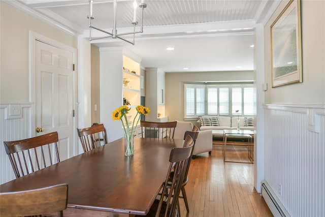 dining area featuring beam ceiling, ornamental molding, wood-type flooring, wainscoting, and a baseboard radiator