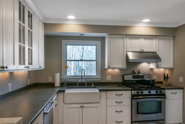 kitchen featuring under cabinet range hood, a sink, dark countertops, white cabinetry, and appliances with stainless steel finishes