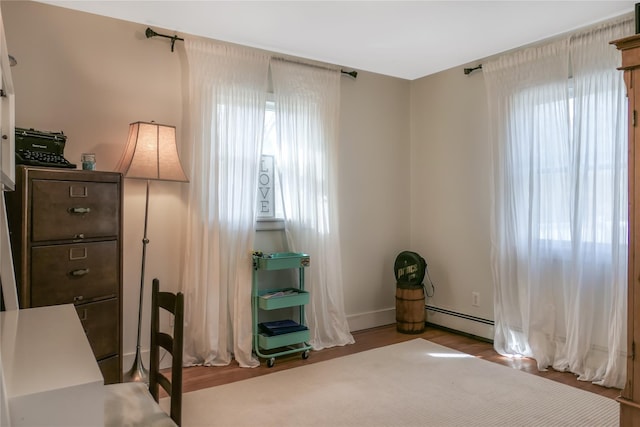 interior space featuring a baseboard heating unit and wood finished floors