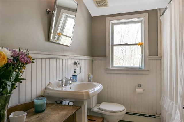 full bath with a shower with shower curtain, a wainscoted wall, visible vents, a baseboard radiator, and toilet