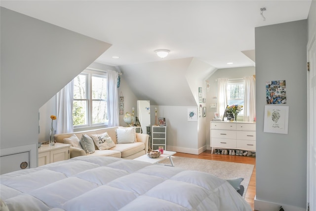 bedroom featuring multiple windows, light wood-type flooring, baseboards, and vaulted ceiling