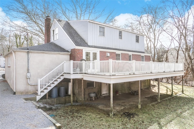 back of property featuring stairway, a shingled roof, a wooden deck, brick siding, and a chimney