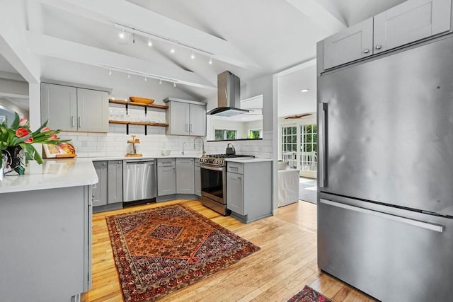 kitchen featuring gray cabinetry, vaulted ceiling, decorative backsplash, island exhaust hood, and stainless steel appliances