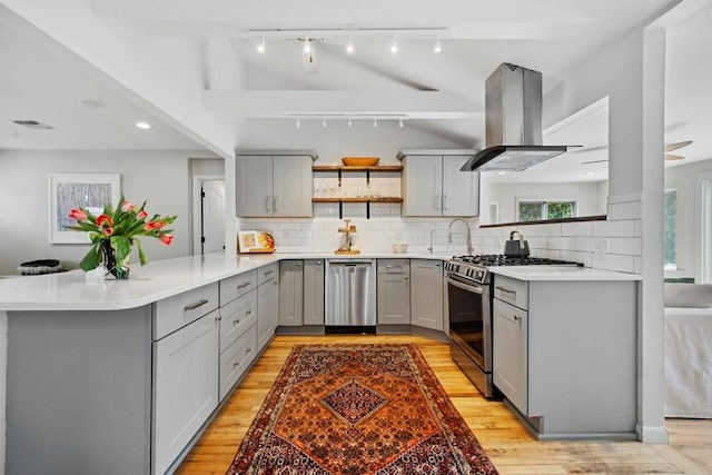 kitchen with gray cabinets, open shelves, appliances with stainless steel finishes, a peninsula, and island range hood