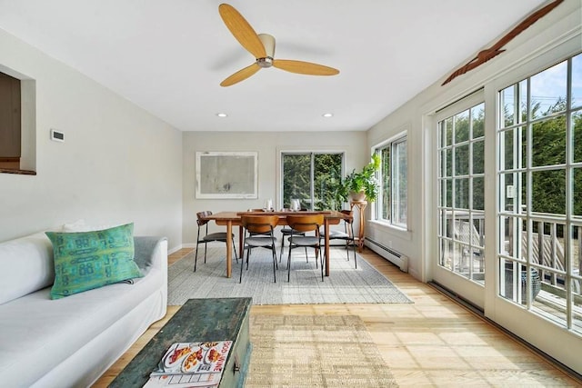 sunroom / solarium featuring a baseboard heating unit and ceiling fan