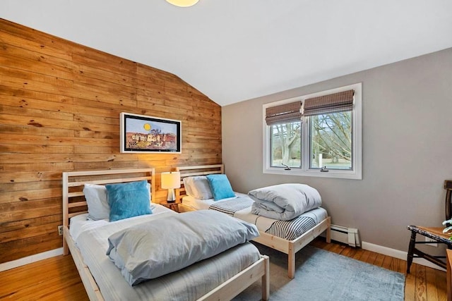 bedroom with wood-type flooring, wooden walls, baseboards, baseboard heating, and vaulted ceiling