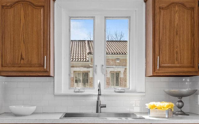 kitchen featuring brown cabinetry, tasteful backsplash, light countertops, and a sink