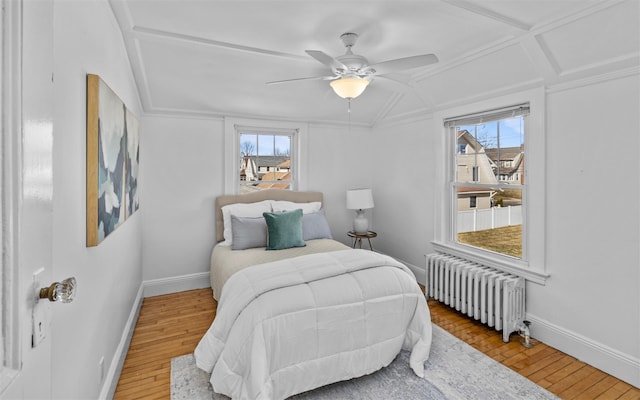 bedroom featuring hardwood / wood-style flooring, radiator heating unit, a ceiling fan, and baseboards