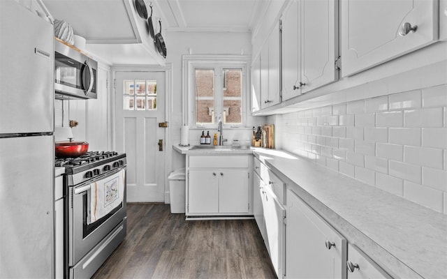 kitchen with tasteful backsplash, light countertops, appliances with stainless steel finishes, white cabinetry, and a sink