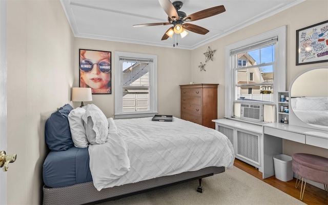 bedroom with multiple windows, radiator heating unit, wood finished floors, and ornamental molding