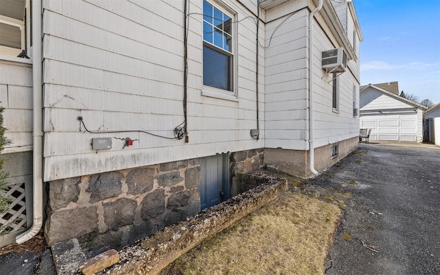 view of property exterior with an outbuilding and a wall unit AC