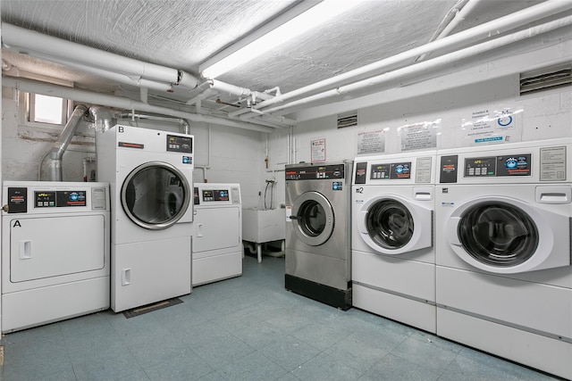 community laundry room with washer and dryer, light floors, and a sink