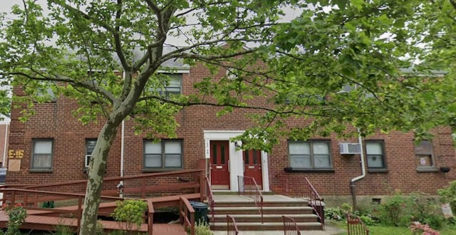 view of front of property featuring brick siding and a wall mounted AC