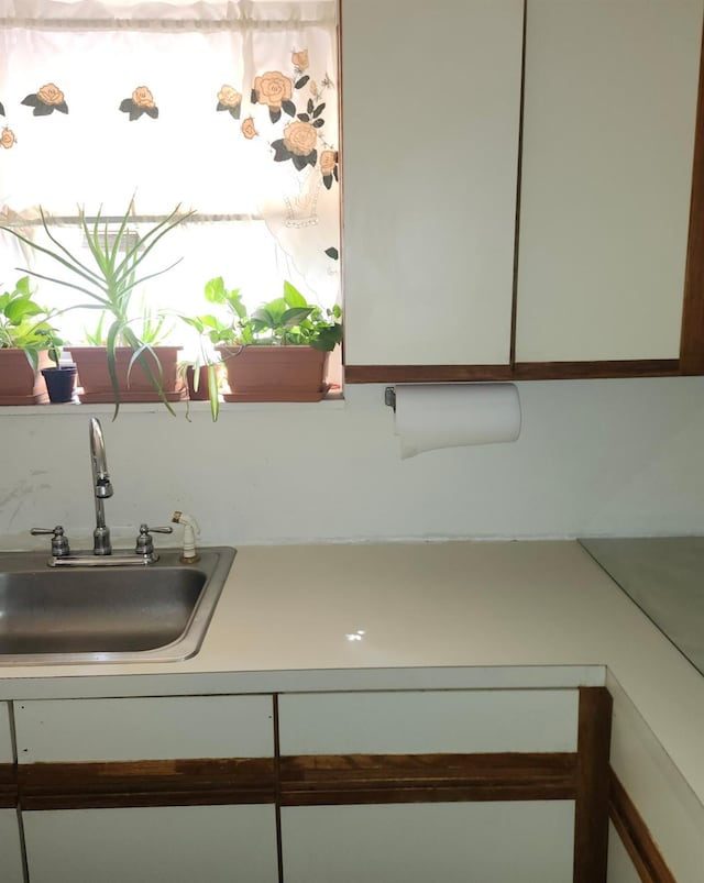 interior space featuring a sink, white cabinets, and light countertops