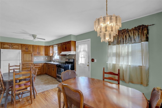 dining space featuring light wood-style flooring and ceiling fan with notable chandelier