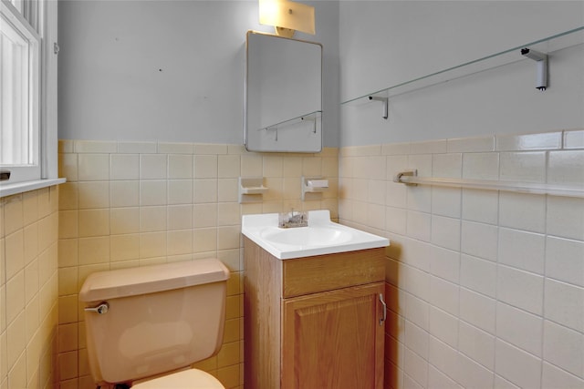 bathroom with vanity, tile walls, toilet, and a wainscoted wall