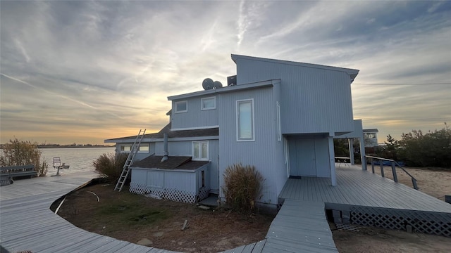 back of property at dusk with a deck with water view