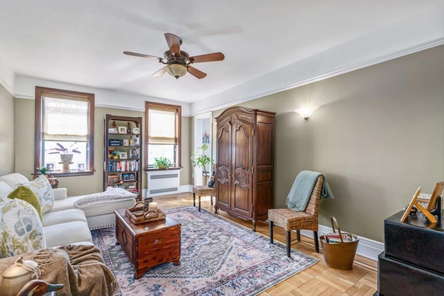 living room featuring a ceiling fan, radiator heating unit, and baseboards