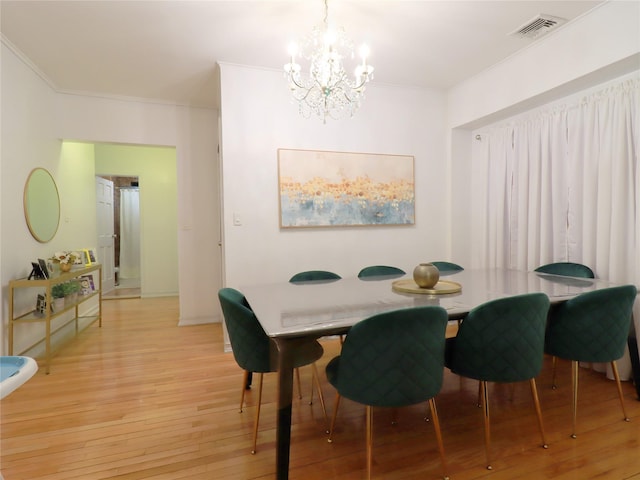 dining space featuring light wood-type flooring, visible vents, a notable chandelier, and ornamental molding