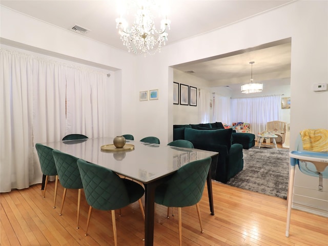 dining space with an inviting chandelier, light wood-style flooring, and visible vents