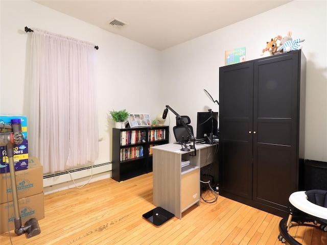 office space featuring visible vents, light wood-type flooring, and a baseboard heating unit