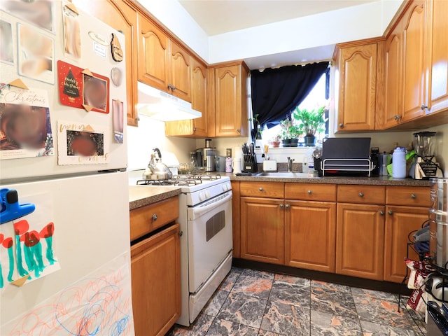 kitchen with under cabinet range hood, stone finish flooring, white appliances, and brown cabinetry