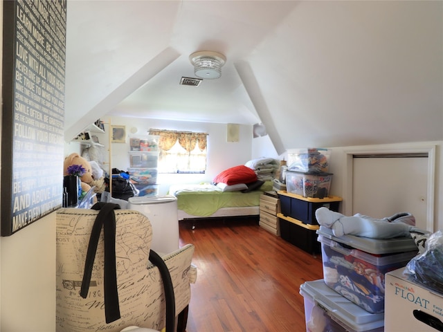 bedroom with vaulted ceiling, wood finished floors, and visible vents