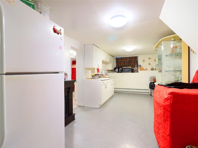 kitchen with a baseboard heating unit, freestanding refrigerator, white cabinets, light countertops, and light floors