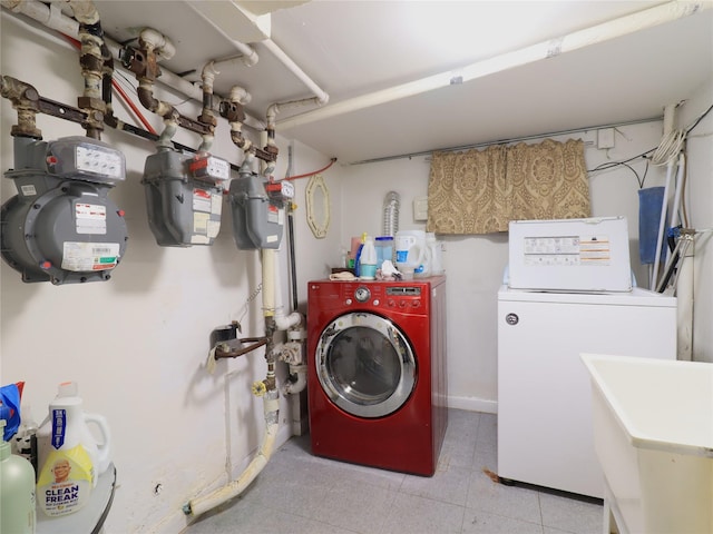 laundry room featuring laundry area, washing machine and dryer, baseboards, and a sink