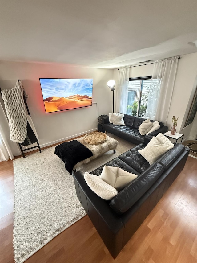 living area with baseboards and wood finished floors