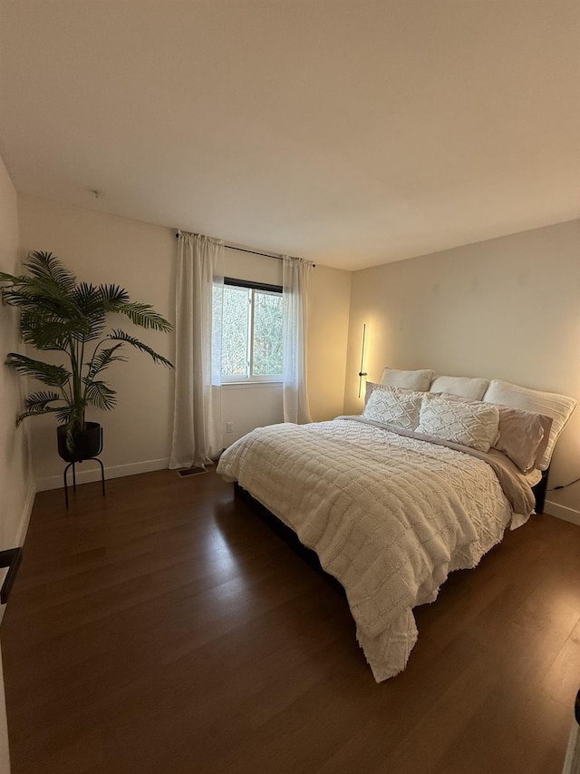 bedroom with dark wood finished floors and baseboards