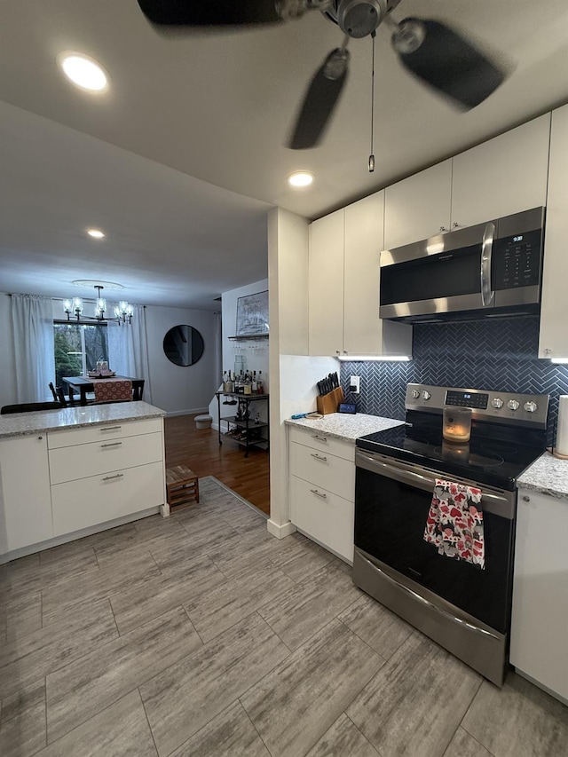 kitchen with decorative backsplash, ceiling fan with notable chandelier, white cabinetry, and stainless steel appliances