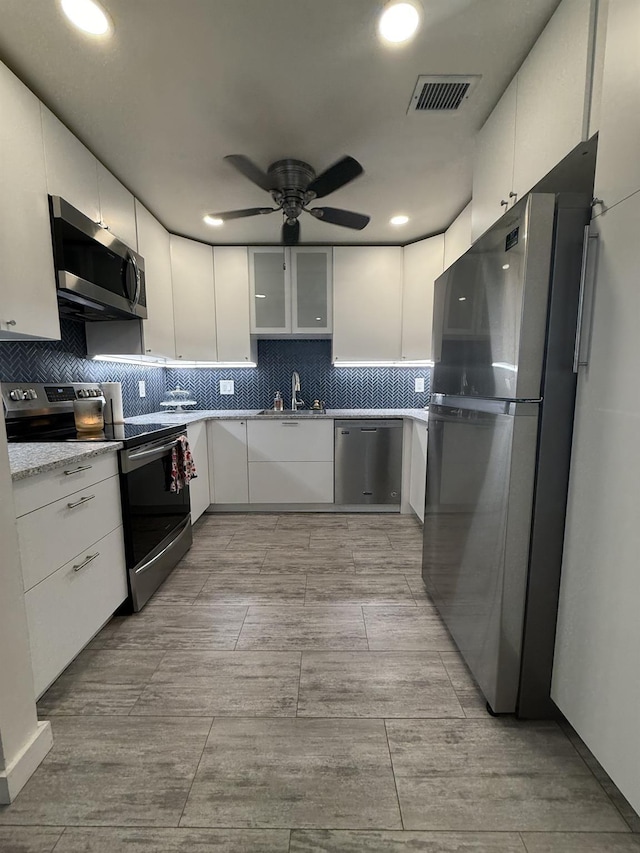 kitchen with visible vents, ceiling fan, a sink, white cabinets, and appliances with stainless steel finishes