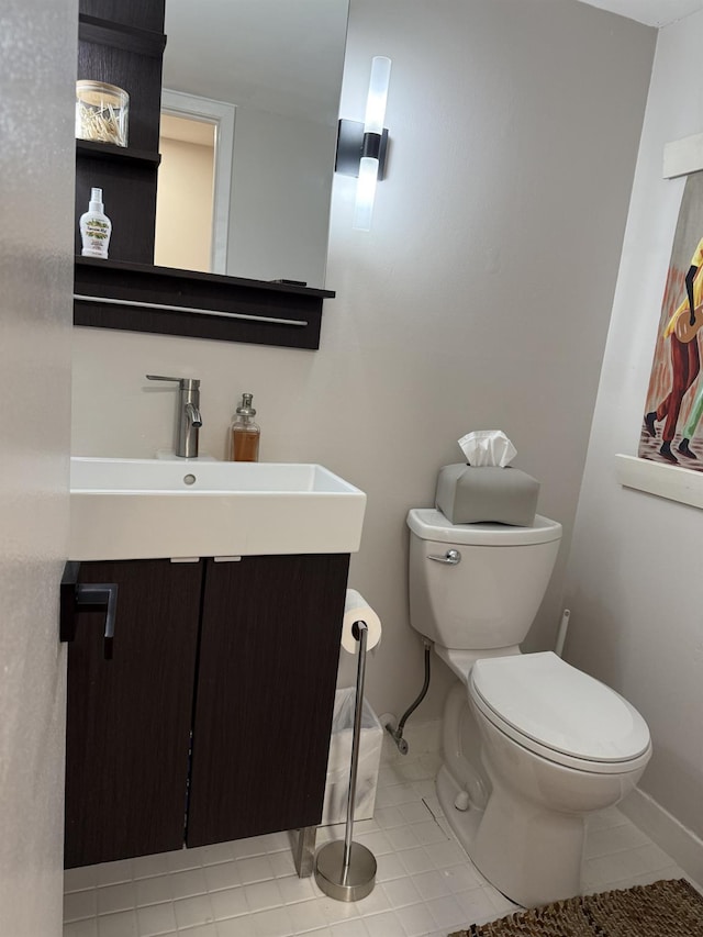 half bathroom featuring tile patterned floors, baseboards, toilet, and vanity