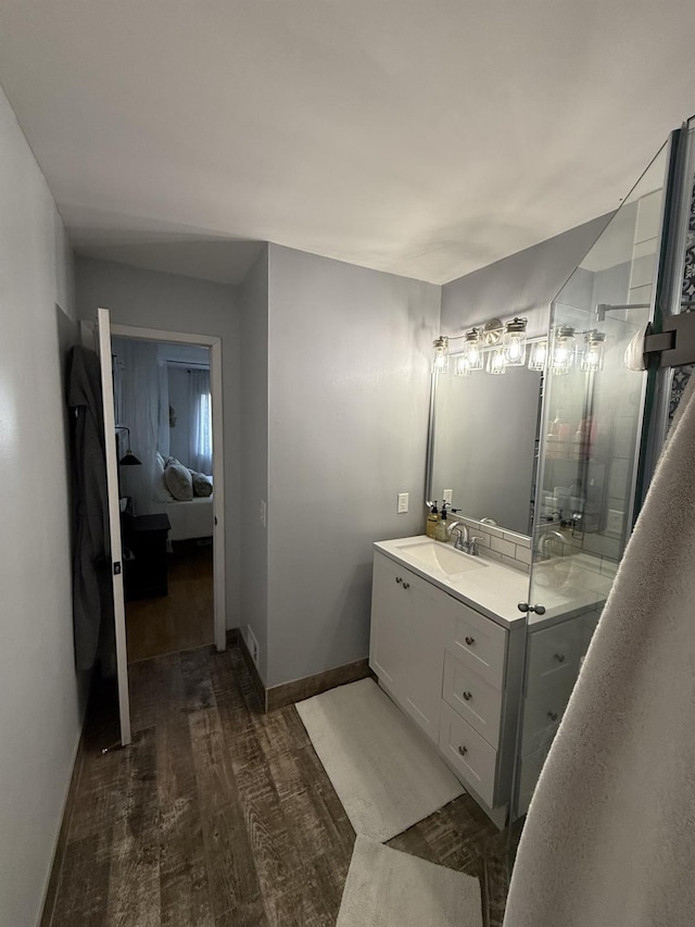 full bathroom featuring a stall shower, baseboards, wood finished floors, and vanity