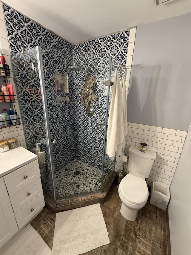 full bathroom with a wainscoted wall, toilet, tile walls, and a stall shower